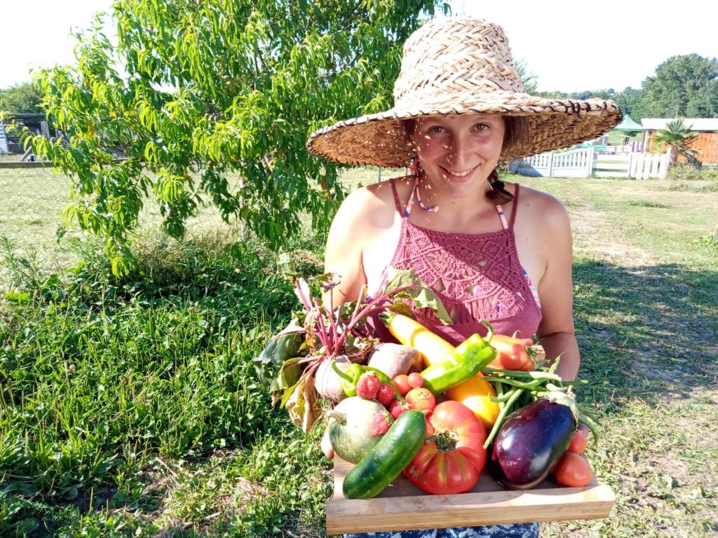 PouillonLa petite ferme de Pouillon - Parc animalier - aire de loisirs的戴着一顶帽子的女人,拿着一盘蔬菜