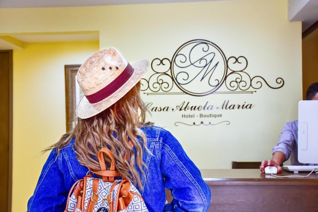 瓦哈卡市Hotel Boutique Casa Abuela Maria的坐在柜台上的戴帽子的女人