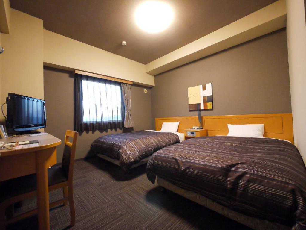 丰川市丰川因特驿前酒店的酒店客房设有两张床、一张桌子和一台电视。