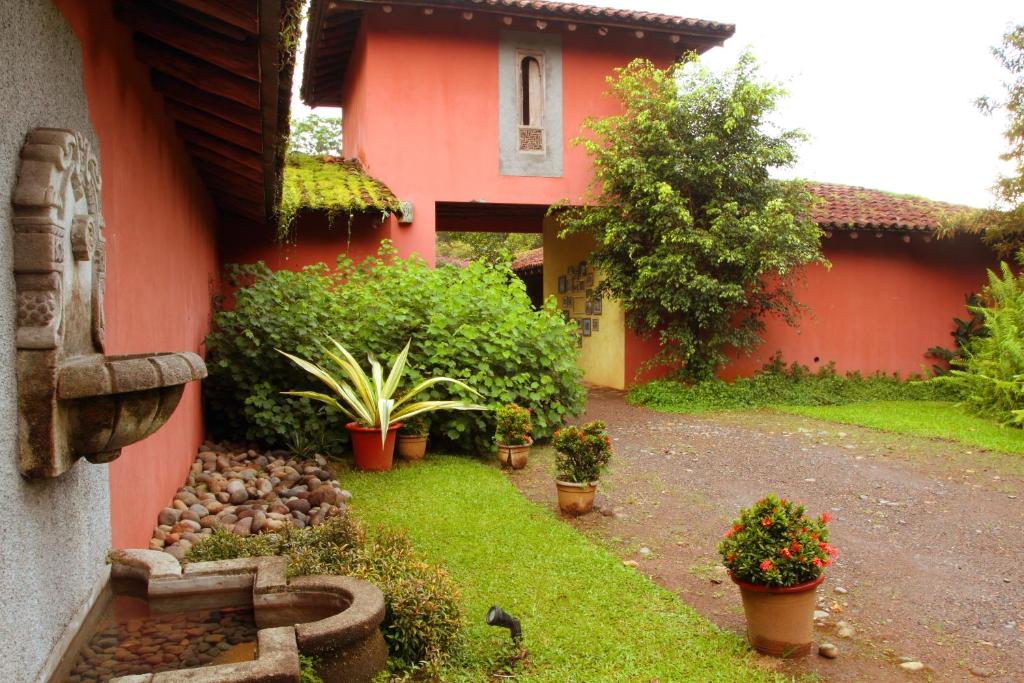 萨拉皮基拉伊斯拉庄园酒店的一座红色的房子,有种有植物和花卉的院子