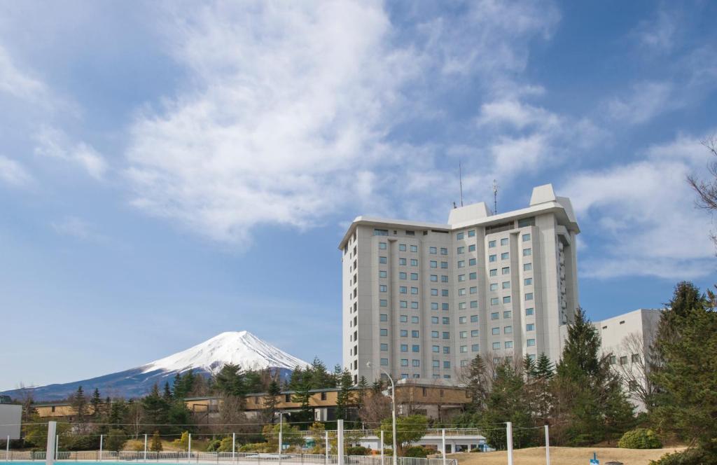 富士吉田市海兰德水疗度假酒店的一座白色的大建筑,背景是一座山