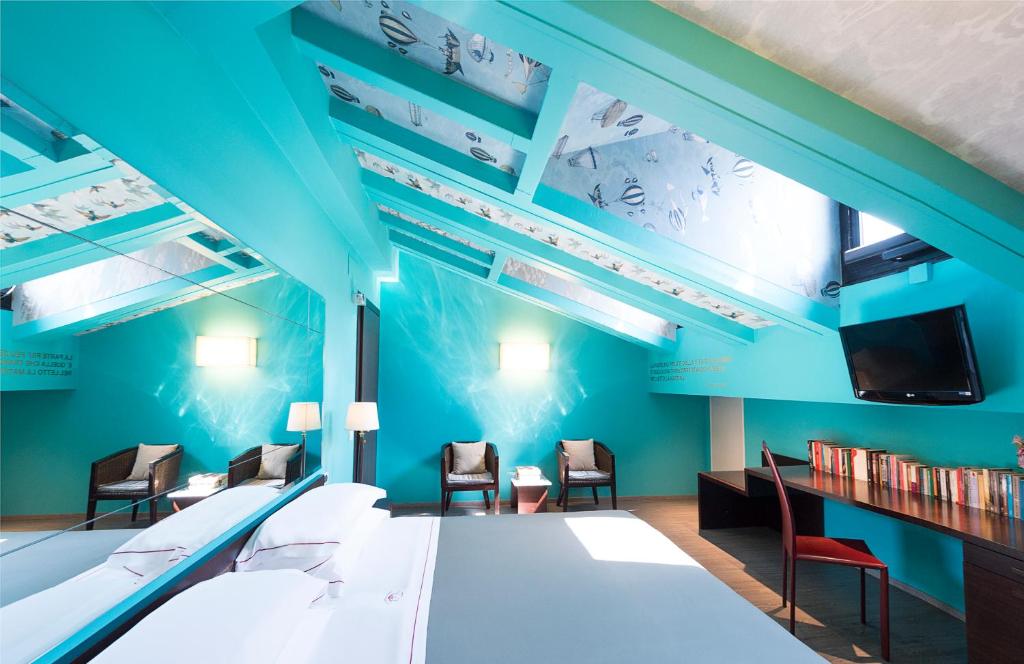 博洛尼亚Phi Hotel Bologna的一间设有蓝色墙壁和椅子以及电视的客房