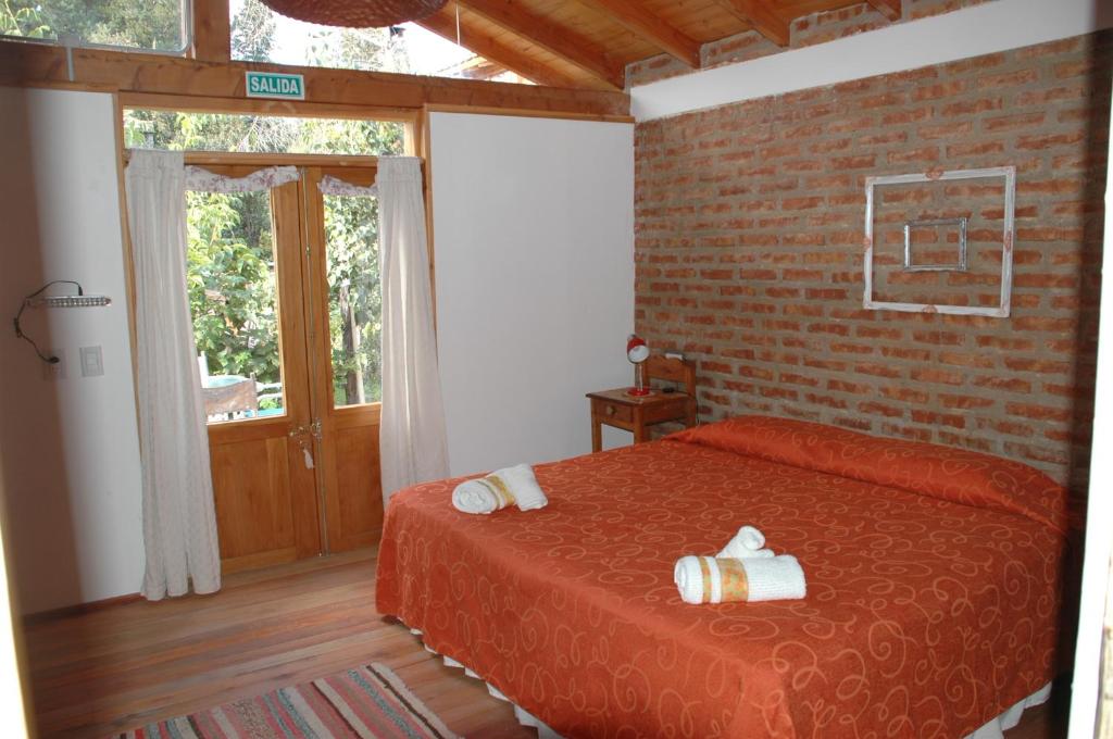 普埃洛湖Cabaña Accesible Ipua的一间卧室设有红色的床和砖墙