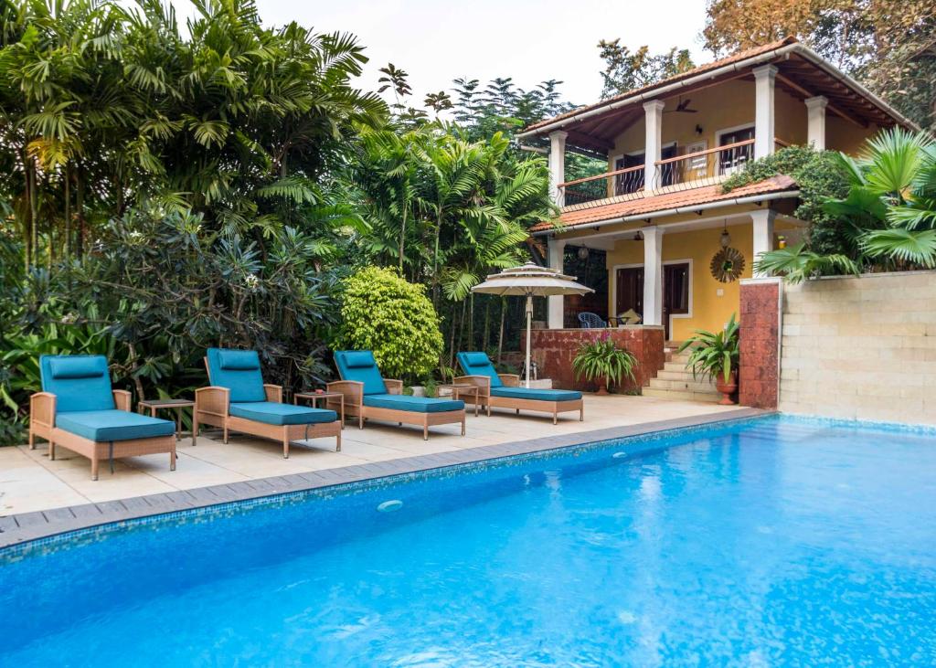 尼禄Serendipity House Goa的一座别墅,设有游泳池、椅子和一座房子