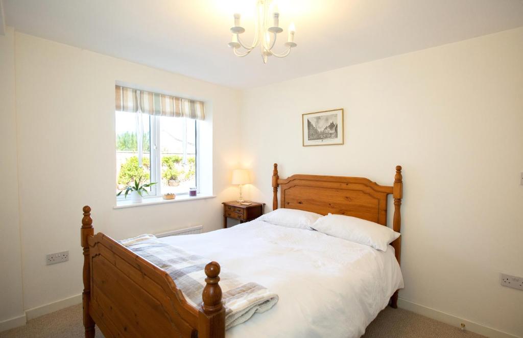 PidleyPERFECT BUSINESS ACCOMMODATION at SIDINGS FARM - Luxury Cottage Accommodation - Self Catering - Secure Parking - Fully equipped Kitchen - Towels & Linen included的一间卧室配有一张木床和吊灯