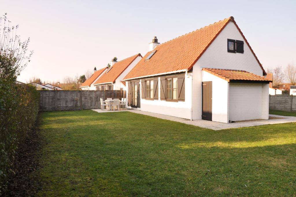 布列登Zeepark Zeewind的一座白色的房子,有橙色的屋顶和院子
