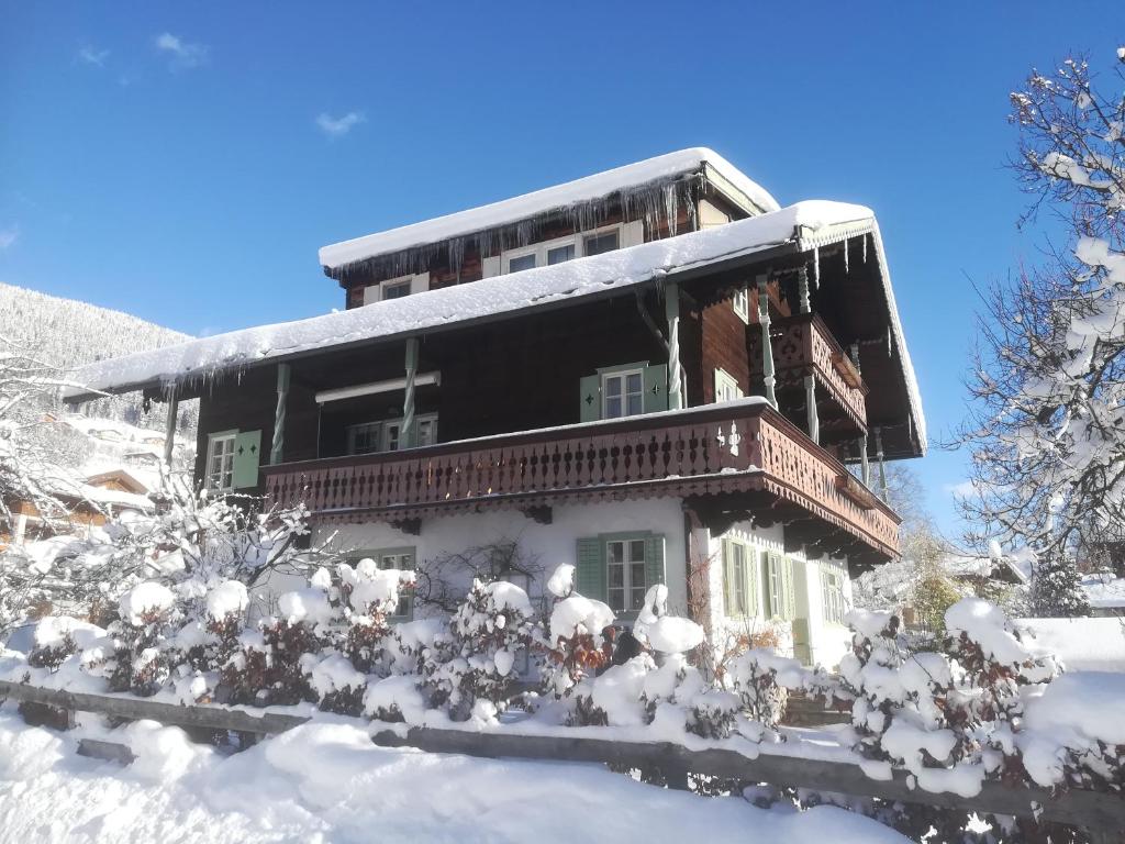 维尔德科格尔山麓布兰贝格Villa Zeppelin - App Smaragd的一座被雪覆盖的房屋,里面布满了树木和灌木