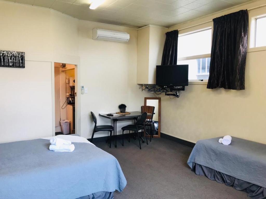 OtautauOtautau Hotel的客房设有两张床、一张桌子和一台电视机。