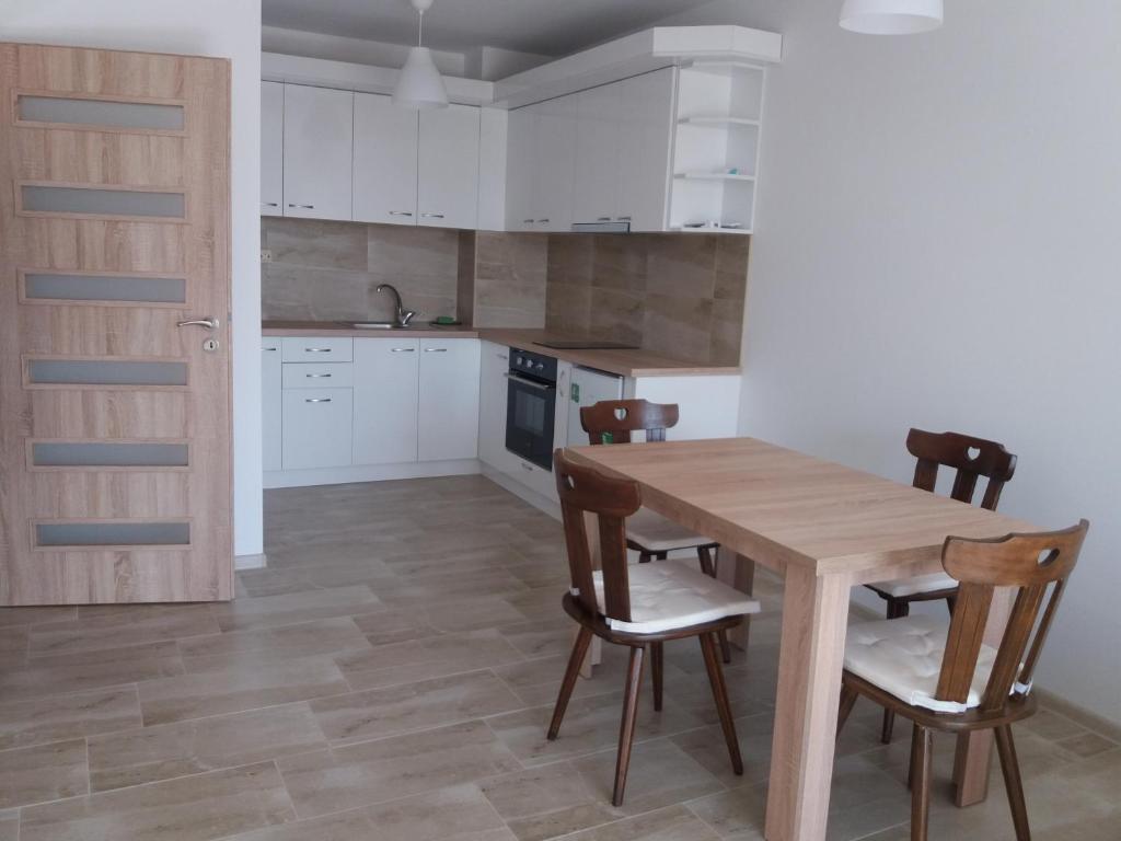 布拉戈耶夫格勒Лукс апартамент Алекс的厨房配有白色橱柜和木桌及椅子