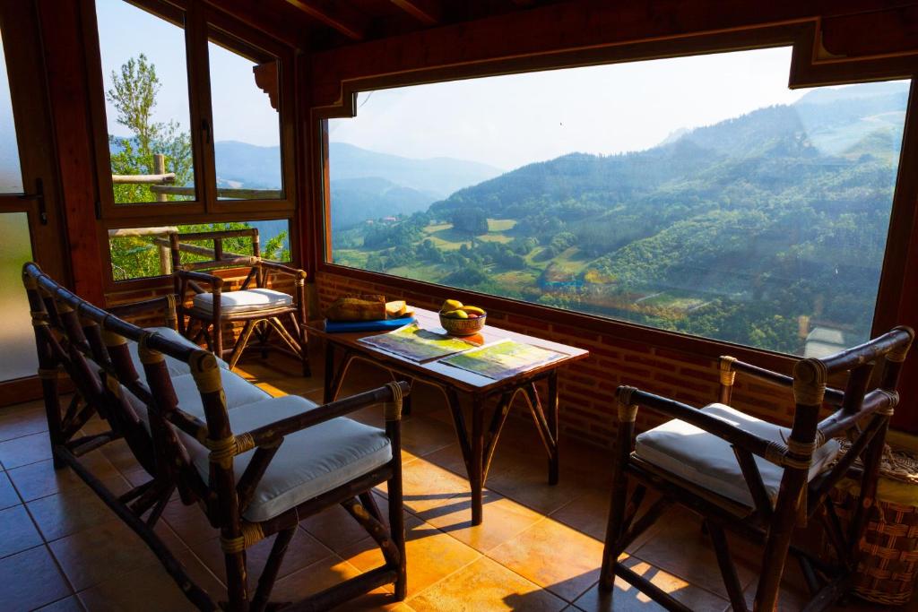 Leintz-Gatzaga阿特贝乡村民宿的客房设有桌椅和大窗户。