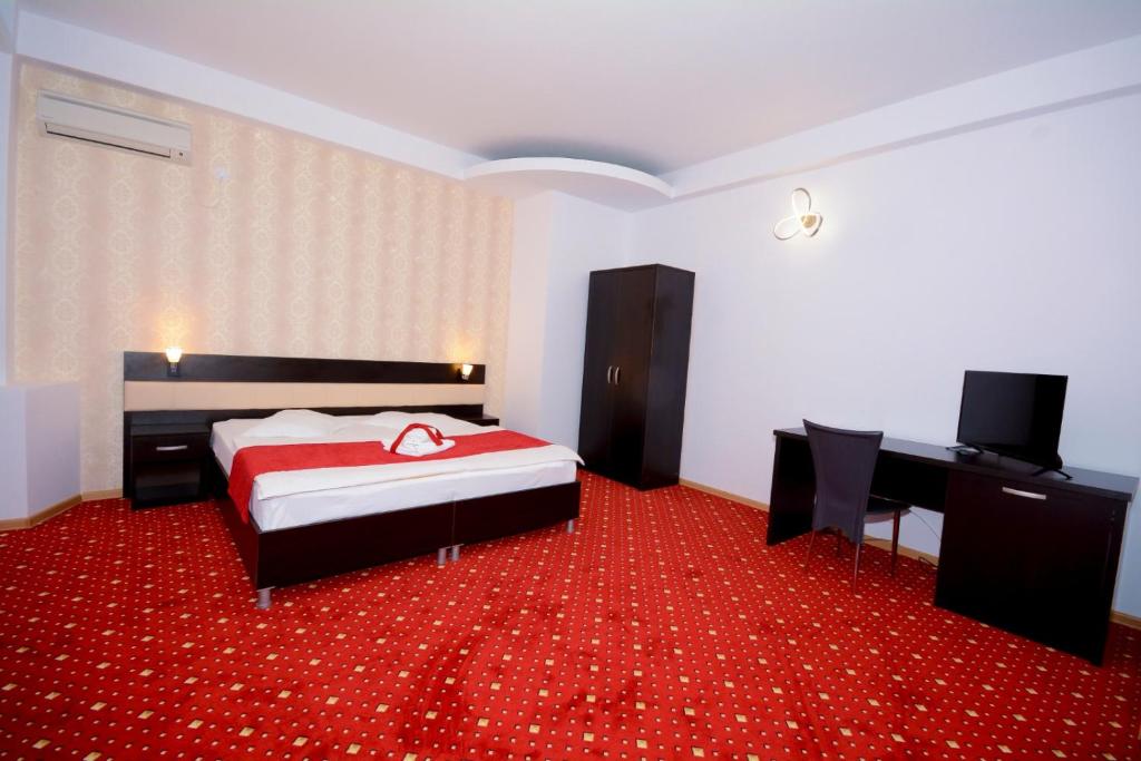 皮特什蒂市中心魔力酒店的一间卧室配有一张床,铺有红色地毯