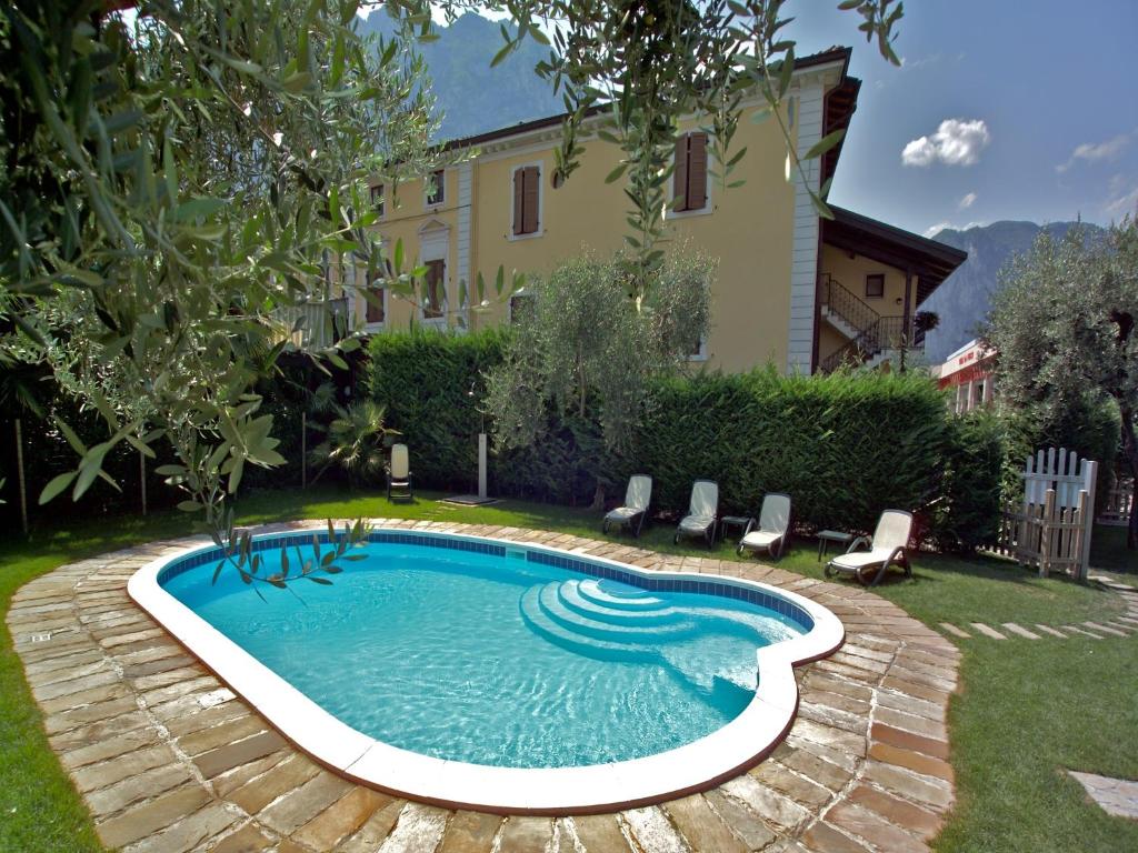 加尔达湖滨Residence Villa degli Aranci的一个带椅子的庭院和房子的游泳池
