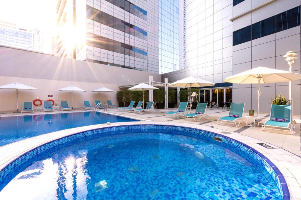 阿布扎比阿布扎比首都中心高级宾馆的游泳池,带椅子和遮阳伞