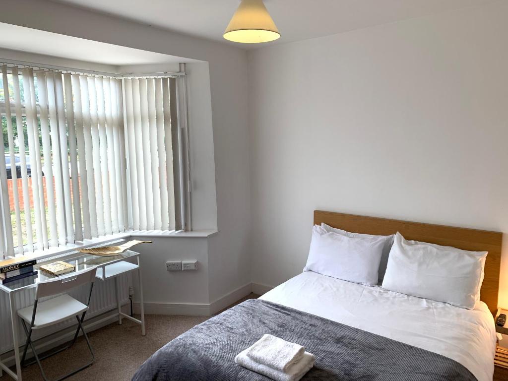 哈姆斯沃思Fresh private bedrooms with private bathroom-1 Bus to Heathrow Airport-5 minutes by car- Helpful advice from our team的卧室配有一张床、一张书桌和窗户。