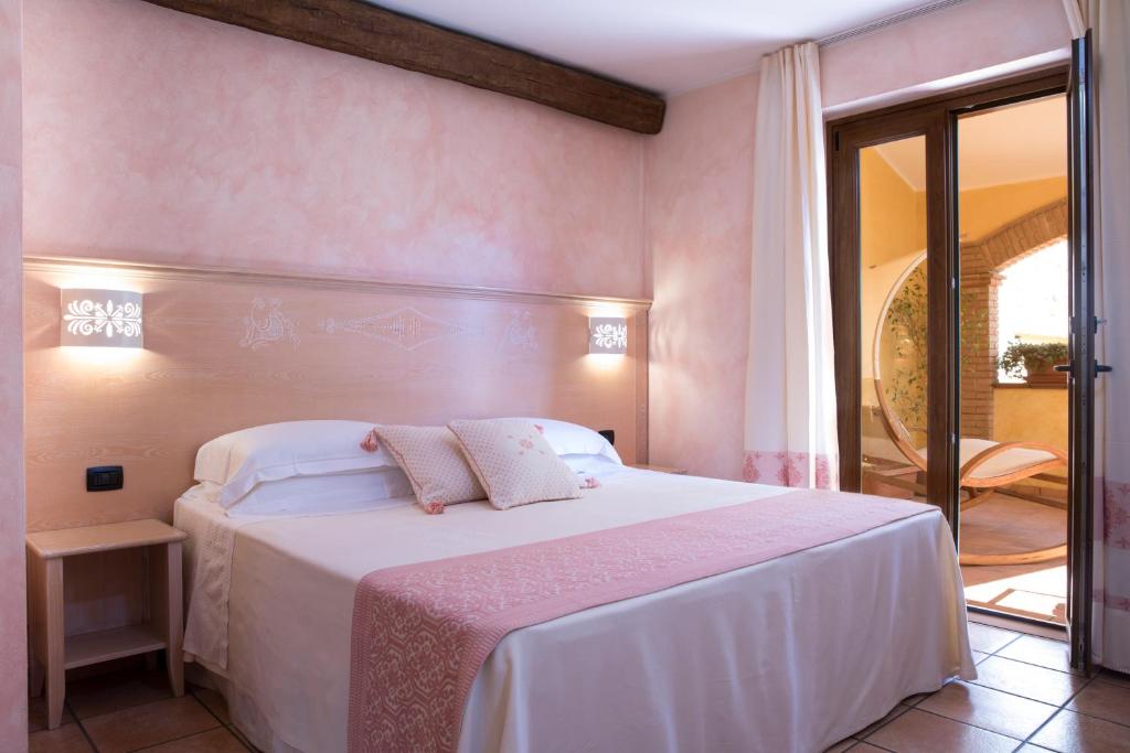 贡内萨S'Anninnia的卧室配有白色大床和粉红色的墙壁