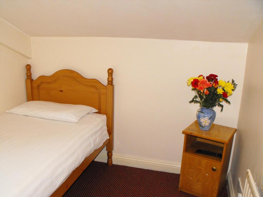 都柏林海泽布鲁克旅舍的一间卧室,配有一张床,桌子上放着花瓶