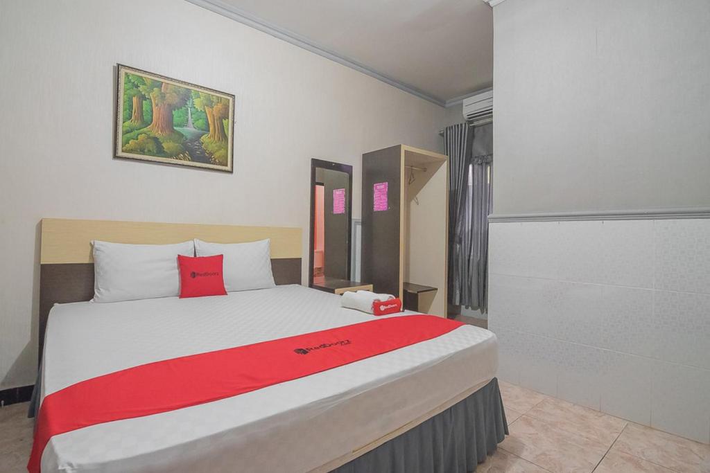 巴厘巴板RedDoorz Syariah near Taman Rozeline Penajam的一间卧室配有一张带红色毯子的大床