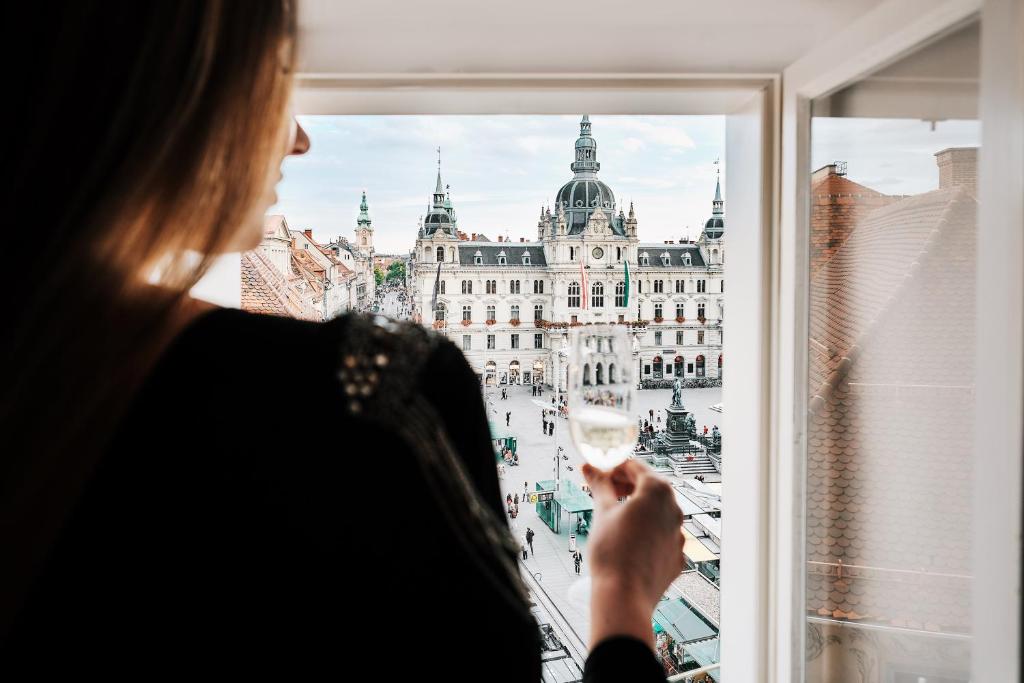 格拉茨Kaiser Apartments - City Centre of Graz的窗户前拿着一杯葡萄酒的女人