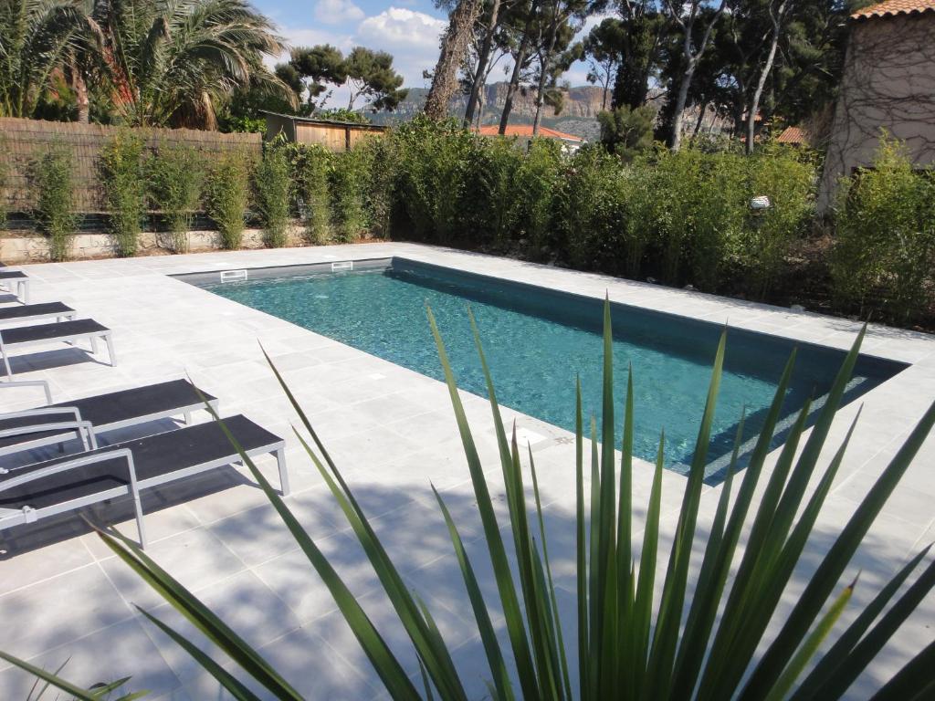 卡西斯Home Cassis - Maison Les Calanques - Piscine chauffée的庭院内的游泳池,带椅子和树木