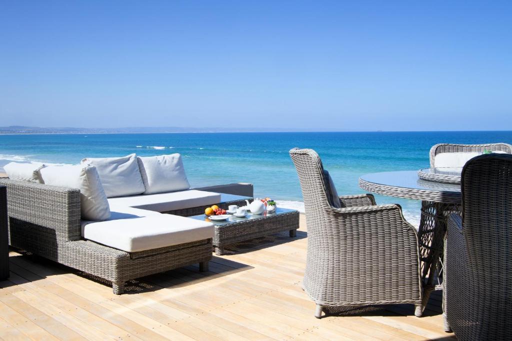 莫塞尔湾Bay Lodge on the Beach的一个带柳条椅和桌子的庭院,享有海景
