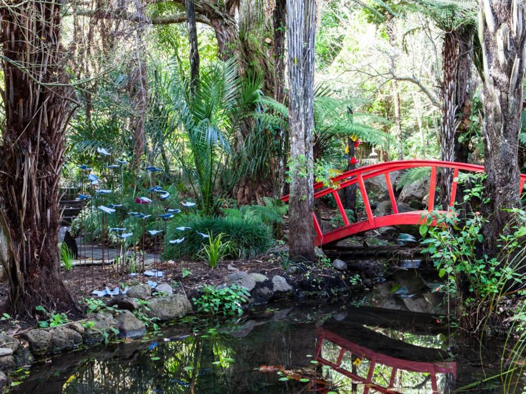 旺阿雷Waimoana Garden Accommodation的花园池塘上的红桥