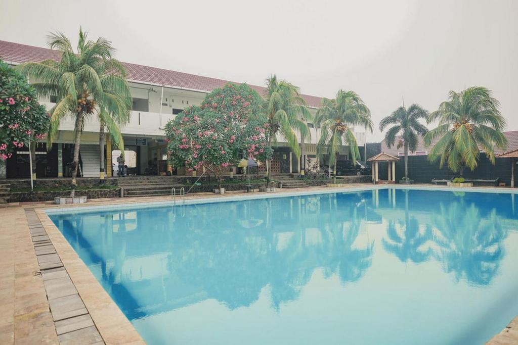 占碑市RedDoorz Syariah @ Pasir Putih Jambi的大楼前的大型蓝色游泳池