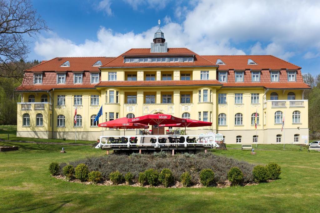叙尔茨哈Ferien Hotel Villa Südharz的前面有雨伞的大型黄色建筑