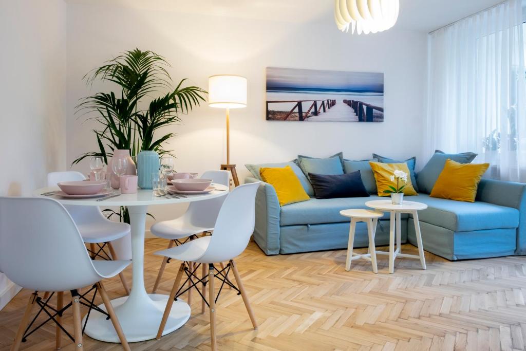 华沙CRISTINE APARTMENT的客厅配有蓝色的沙发、桌子和椅子