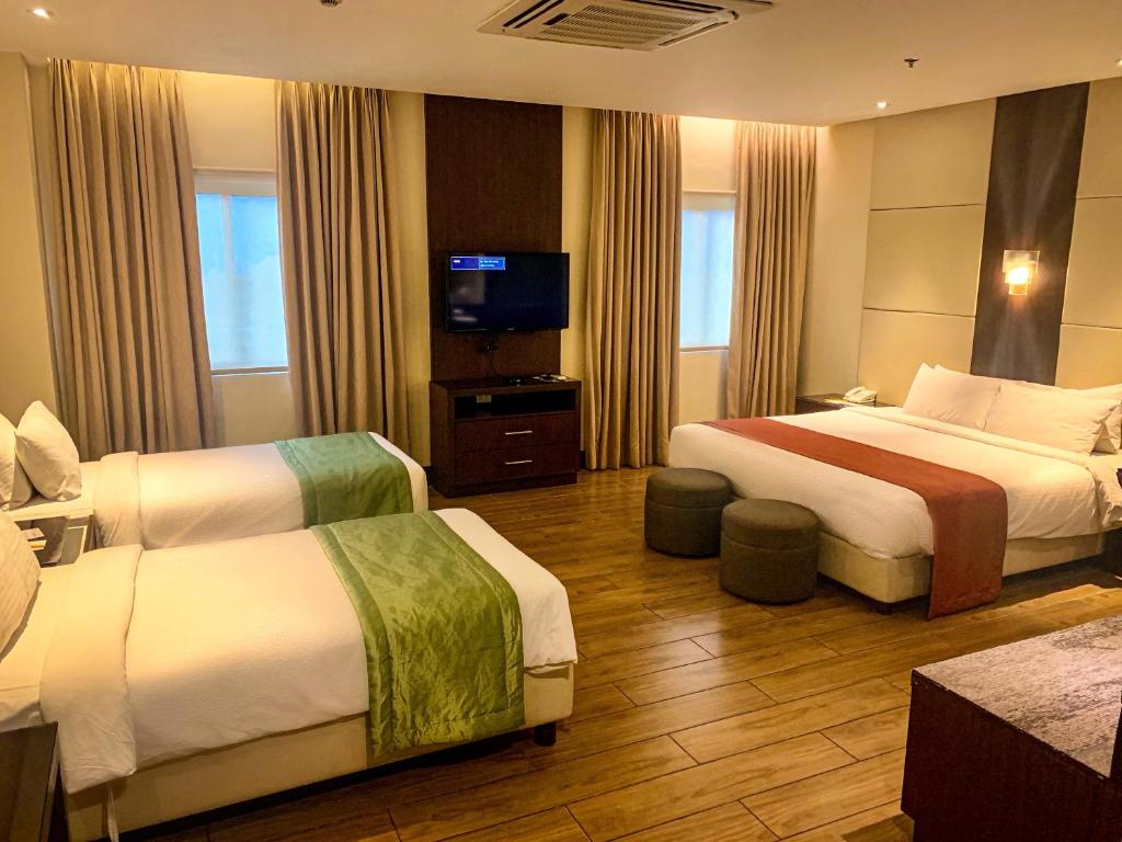 大雅台Hotel Monticello Tagaytay的酒店客房设有两张床和一台平面电视。