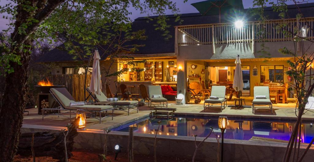 侯斯普瑞特Ukuthula Bush Lodge的后院设有游泳池、椅子和房屋