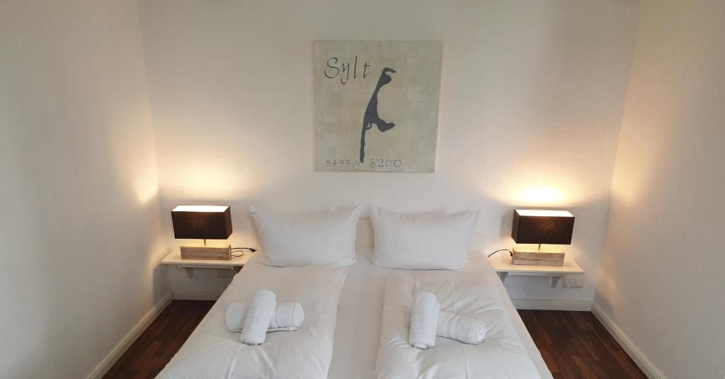 韦斯特兰邦姆霍夫叙尔特岛旅馆的一间卧室配有一张带白色床单和两盏灯的床。