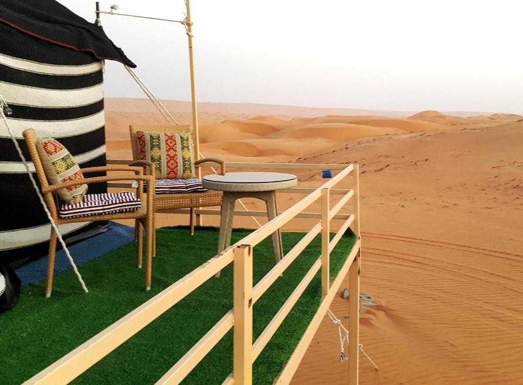 Al WāşilHamood desert local camp的沙漠中的一张桌子和两把椅子