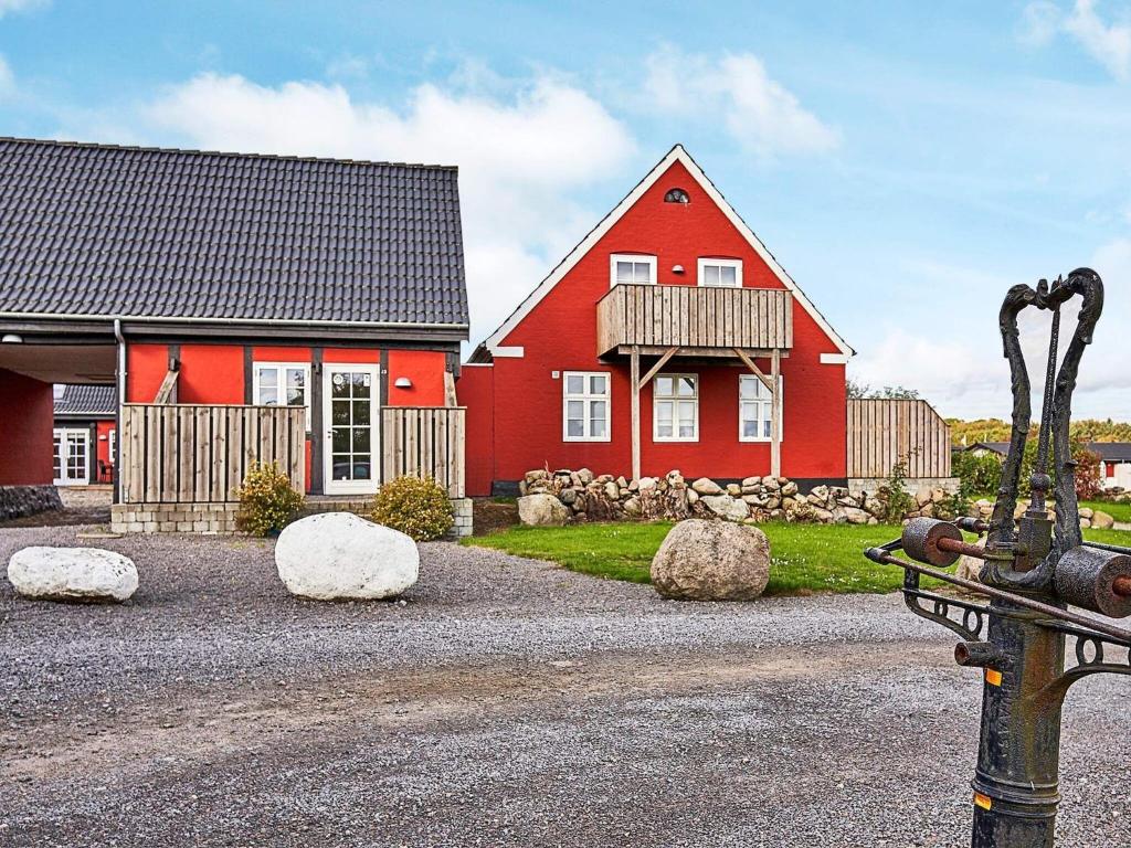 奥基克比5 person holiday home in Aakirkeby的前面有岩石的红色房子