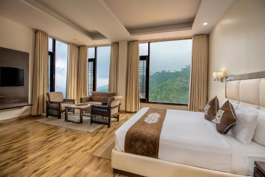 西姆拉Snow Valley Resorts Shimla的酒店客房设有一张床和一个大窗户