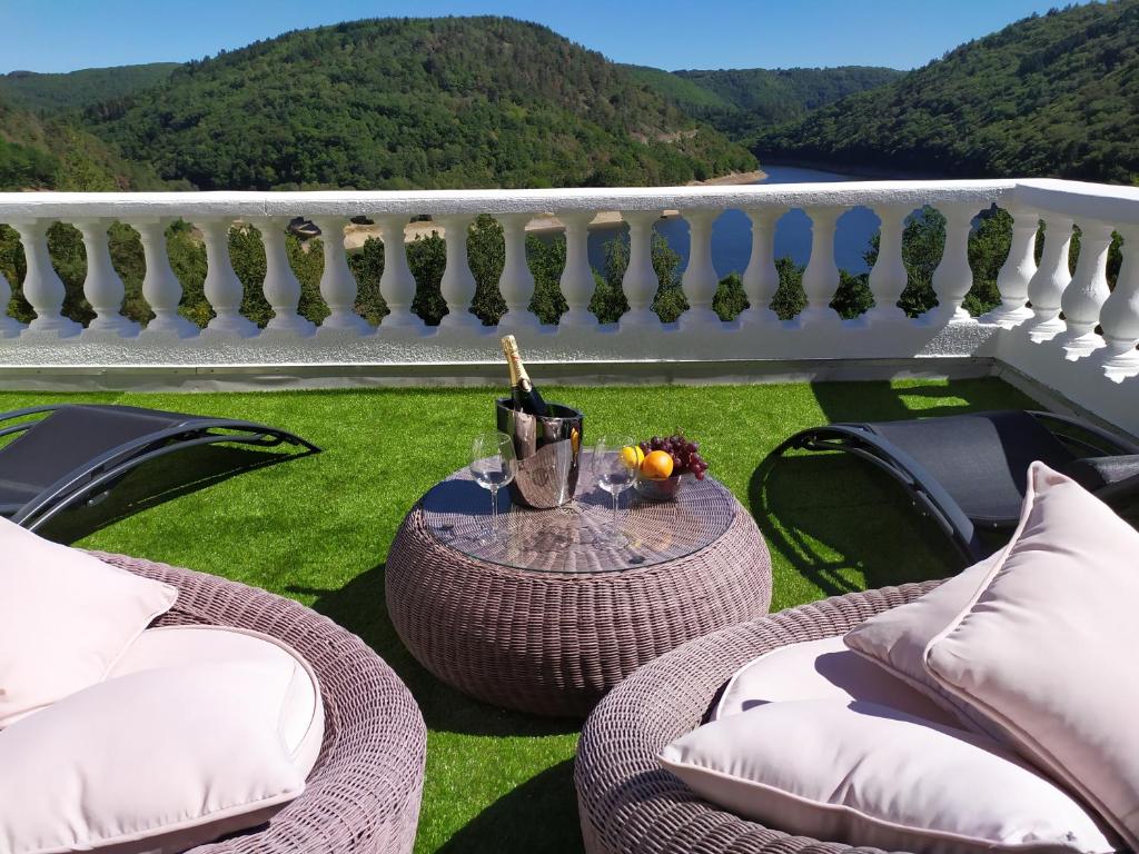 MiremontMa villa au bord de l'eau的阳台配有藤椅和1张带1瓶葡萄酒的桌子。