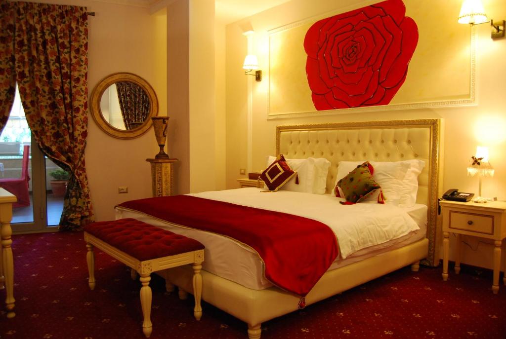 都拉斯2 KITARRAT Boutique Hotel & SPA的卧室配有一张大床,墙上挂着红玫瑰画