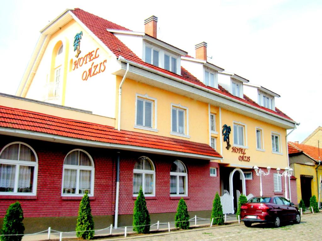 基什孔弗莱吉哈佐奥兹斯艾特姆酒店的一座红色和黄色的建筑,前面有一辆汽车