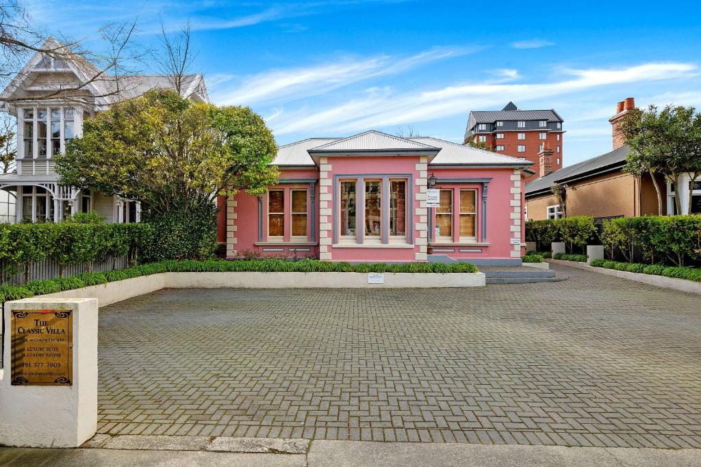 基督城The Classic Villa的前面有砖瓦车道的粉红色房子