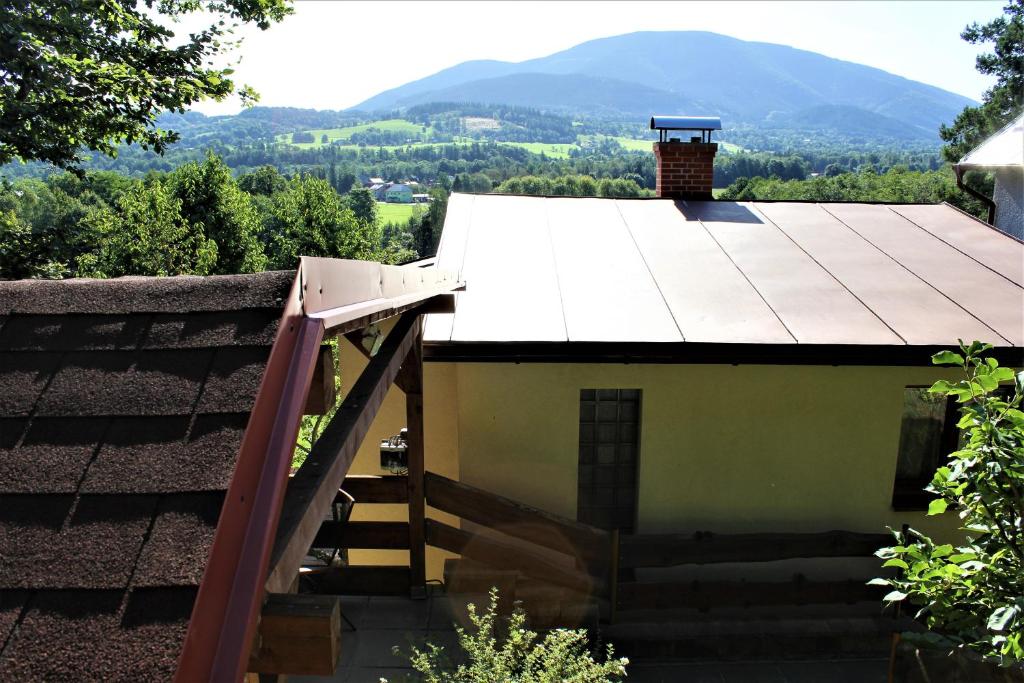 切拉德纳Babiččin Vejminek的房屋设有屋顶,后方设有楼梯和山脉