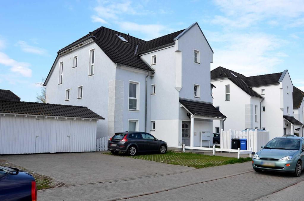 奥斯特巴特宁哈根Ferienwohnung Sandpiper的一座大型白色房子,停车场有车辆停放