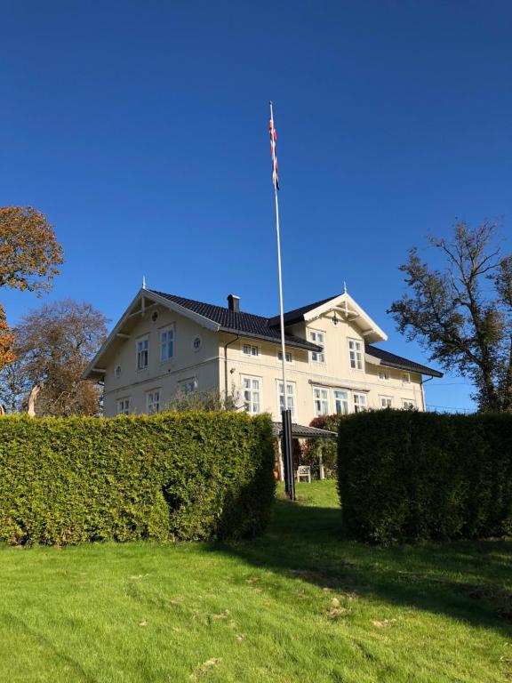 希Gjedsjø Gaard的一座大型白色房子,在柱子上悬挂美国国旗