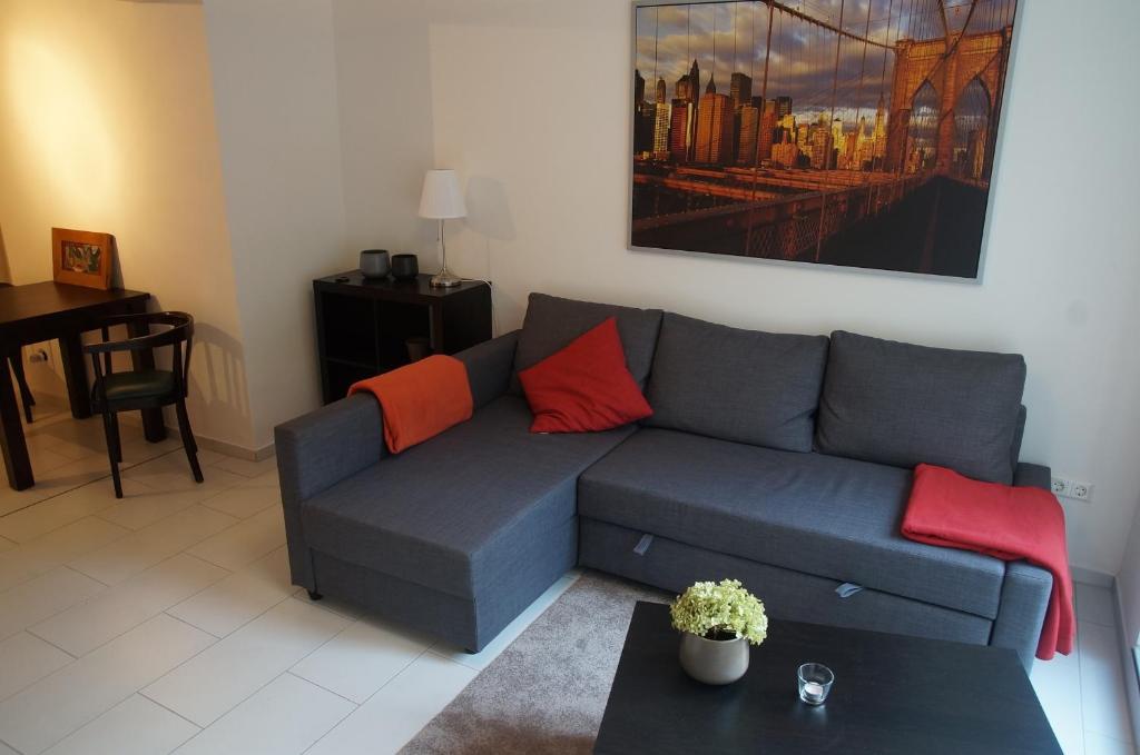 不莱梅豪斯鲁尔曼公寓的客厅配有蓝色沙发和红色枕头
