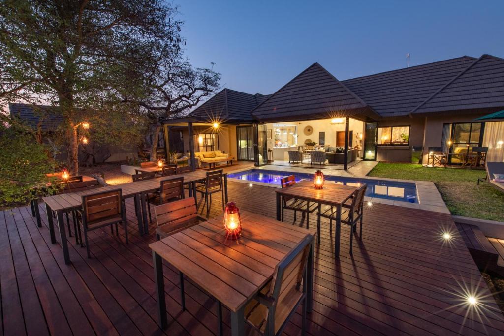 侯斯普瑞特Moya Safari Lodge & Villa的一个带桌椅的甲板和一个游泳池