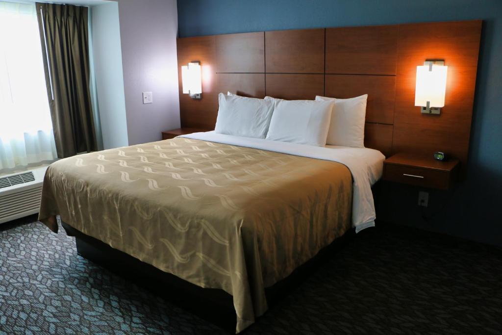 CalciumQuality Inn & Suites Watertown Fort Drum的酒店客房配有一张带白色枕头的大床