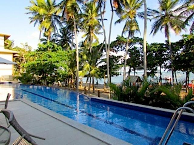 普拉亚多Residencial Enseada Praia do Forte Apto 130的一座棕榈树游泳池毗邻度假酒店