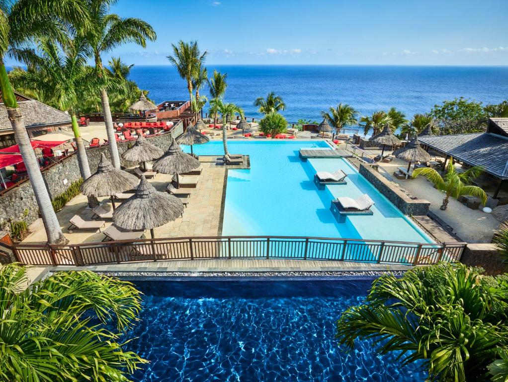 珀蒂蒂勒Palm Hotel & Spa的享有带遮阳伞的泳池和大海的空中景致