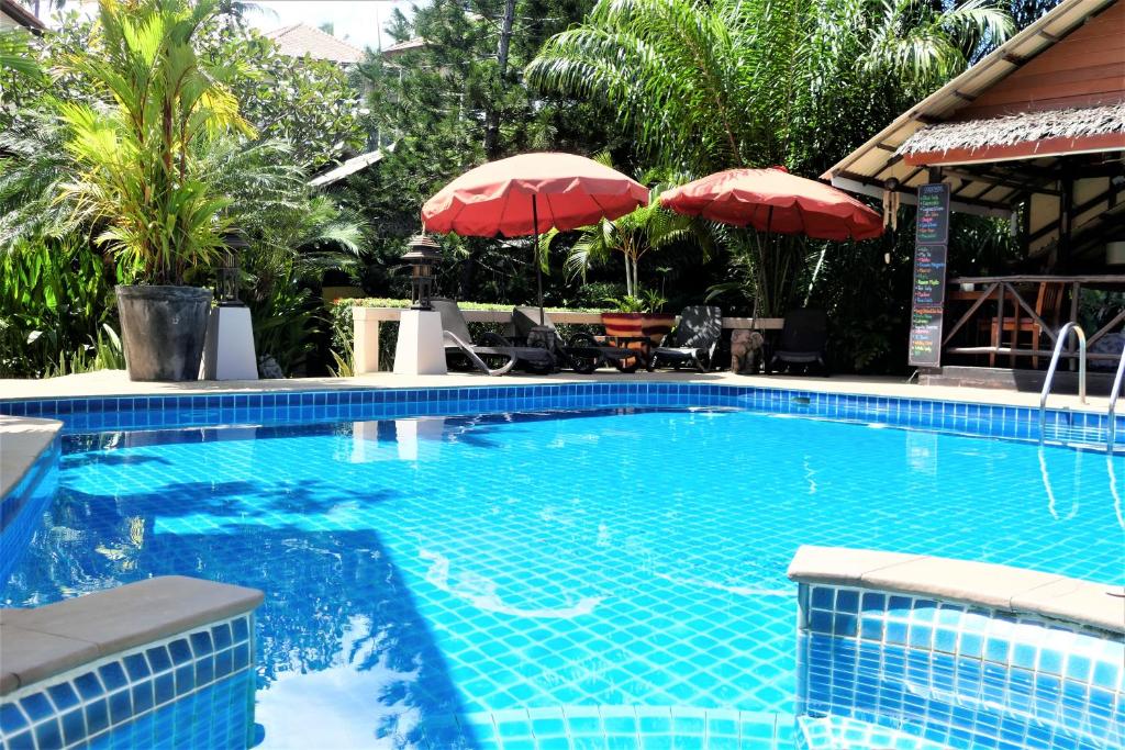 茶云莱海滩班苏瑞普度假酒店的度假村内带红伞的大型游泳池