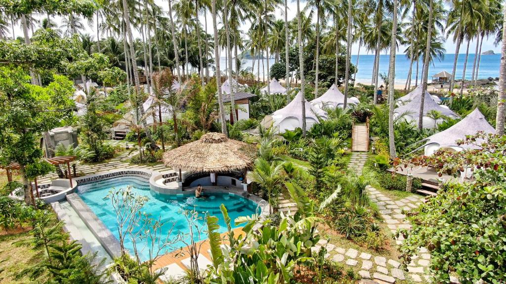 爱妮岛Nacpan Beach Glamping的享有度假村的空中景致,设有游泳池和棕榈树