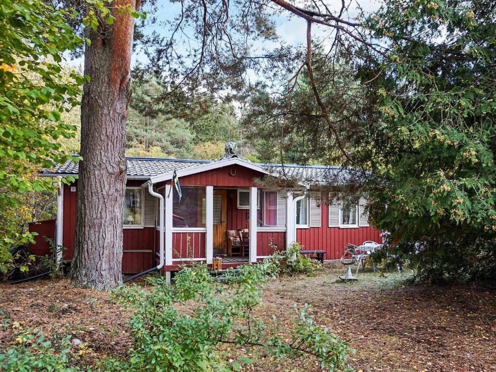Norra Svärdsö6 person holiday home in SORUNDA的前面有一棵树的红色房子
