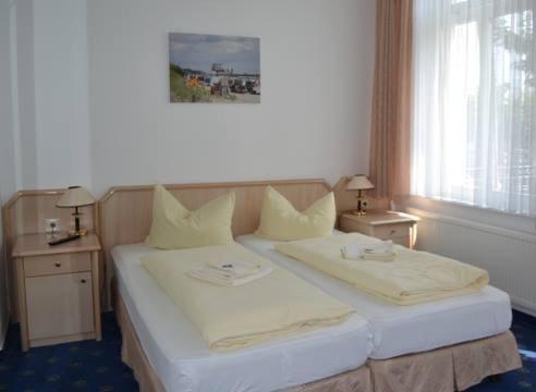 塞巴特阿尔贝克Pension Haus Pommern的一间卧室配有一张带两张桌子和一扇窗户的床。